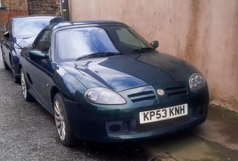 MG TF convertible parked on a gravel driveway.