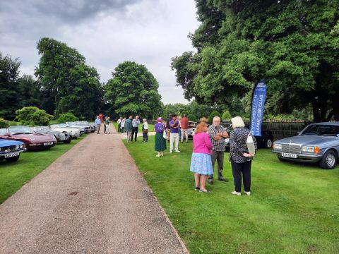 Silver Mercedes-Benz E-Class W124 with attendees at a classic car event.