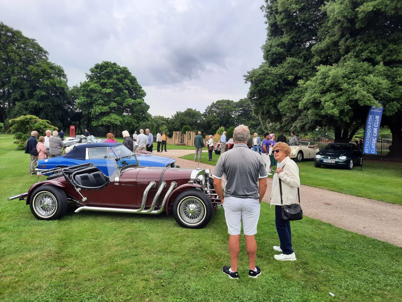 A maroon Morgan Plus 8 convertible at a classic car show with people gathered around.