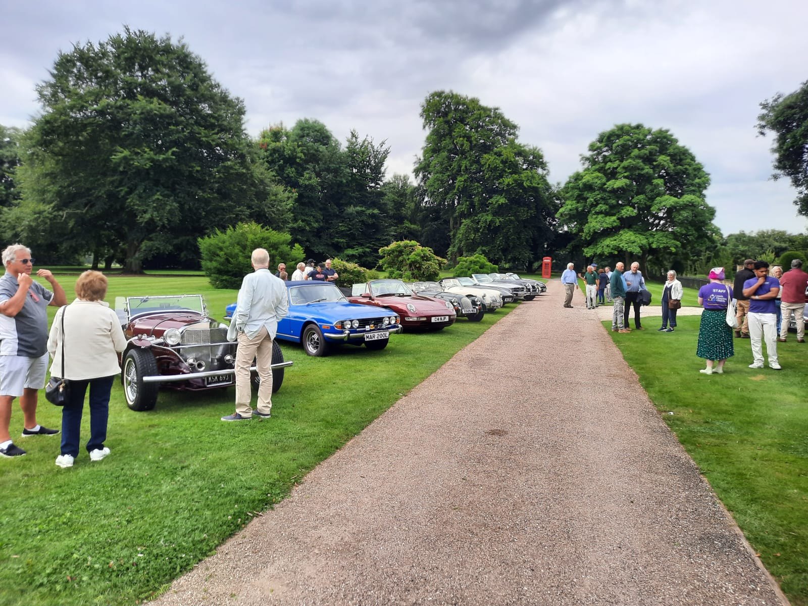 A classic burgundy convertible parked in a line of vintage cars.
