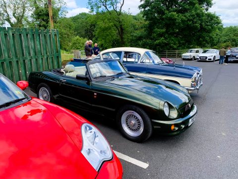 A dark green MG F convertible parked in a classic car show.