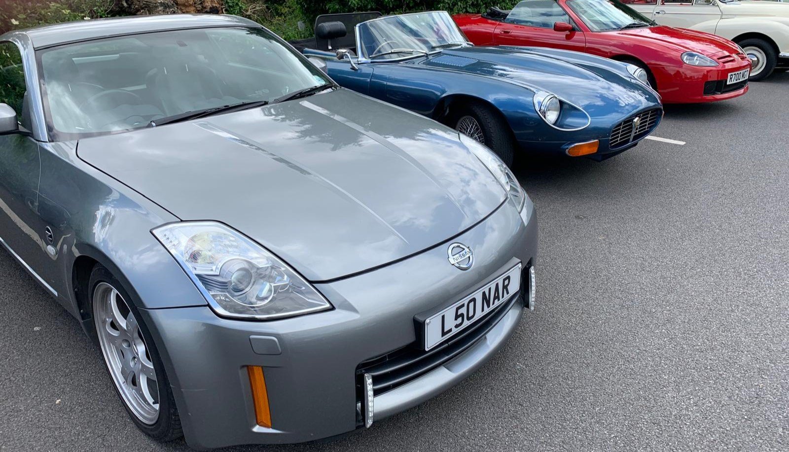 A blue Jaguar E-Type convertible parked among other classic cars.