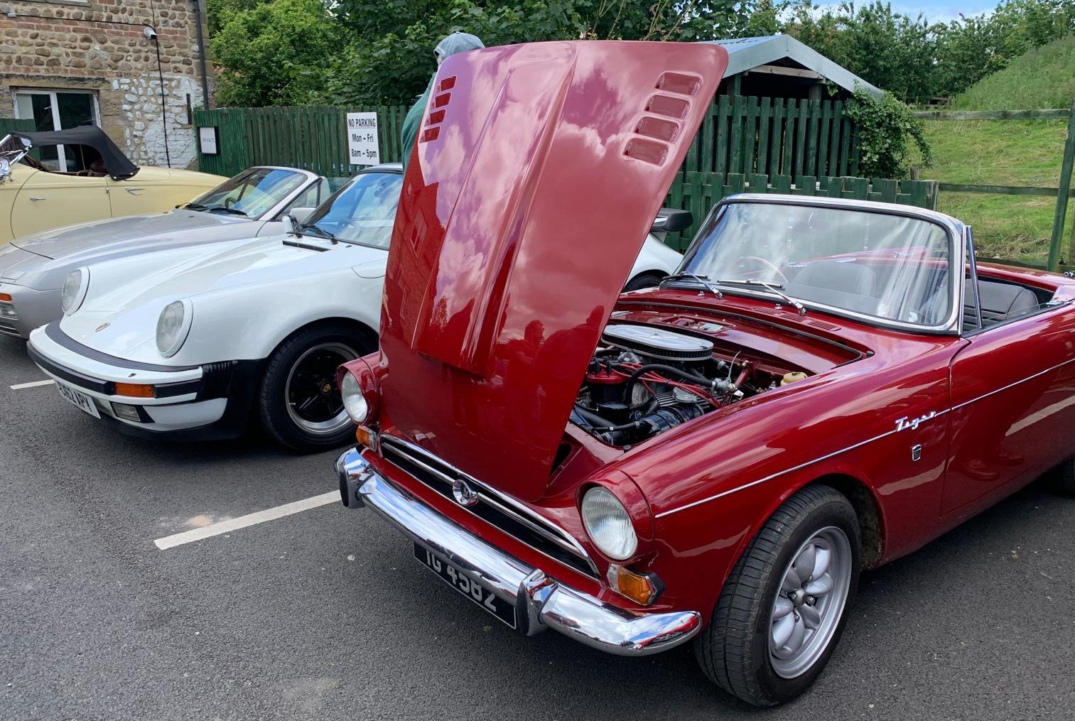A red Triumph Spitfire GT6 with the hood lifted.