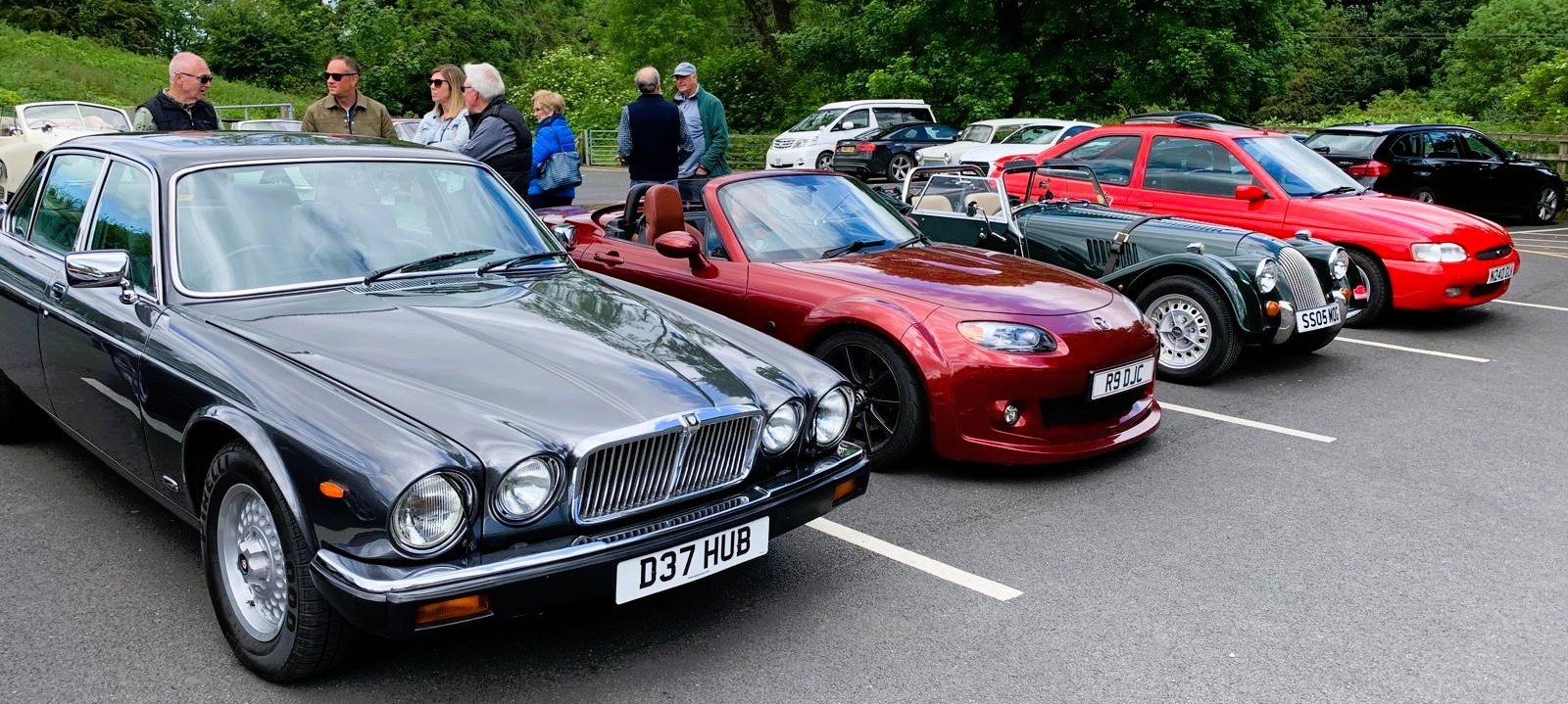 Front view of a black Jaguar XJ40, flanked by other interesting cars.