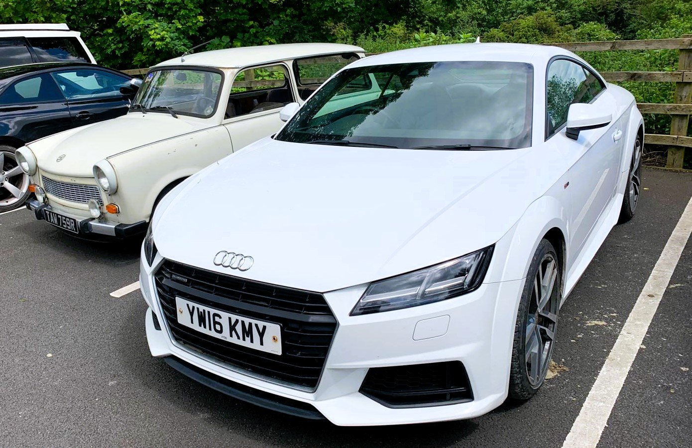 Front view of a white Audi TT parked alongside other classic cars.